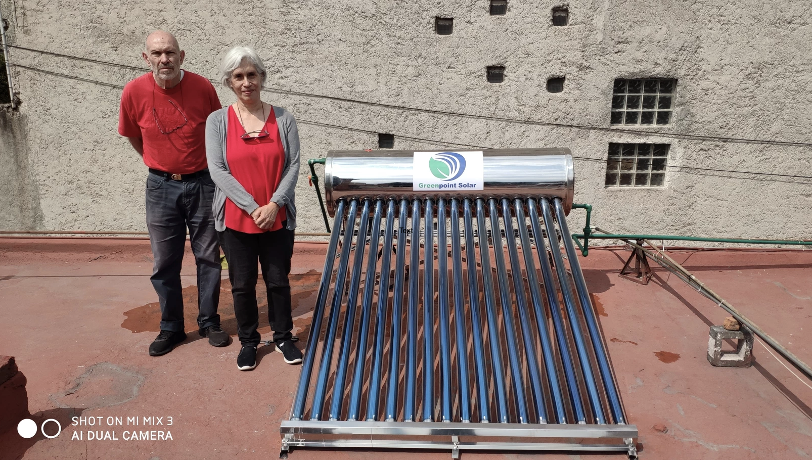 Graviti's customers stand next to their newly purchased solar water heater